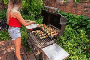 Person grilling vegetable skewers on a propane gas grill outdoors in St. Louis, MO