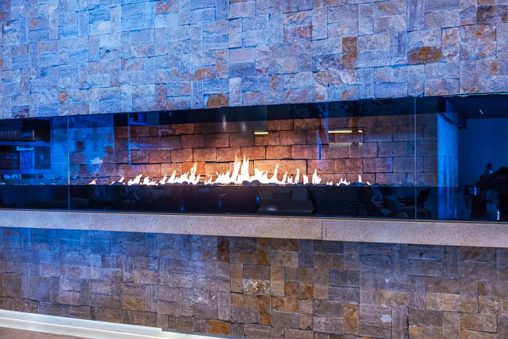Contemporary linear gas fireplace installed within a stone wall in a St. Louis Metro Area home.
